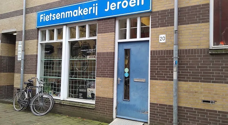 De winkelpui van Fietsenmakerij Jeroen met het blauwe naambord aan de Kastanjeweg.